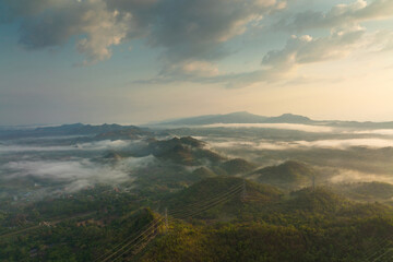 Fog in the morning forest with green mountains and high voltage pole. Pang Puay, Mae Moh, Lampang, Thailand.