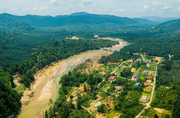 Fototapeta na wymiar Aerial drone view of rural settlements near a river in Hutan Lipur Belukar Bukit, Kuala Berang, Terengganu, Malaysia.