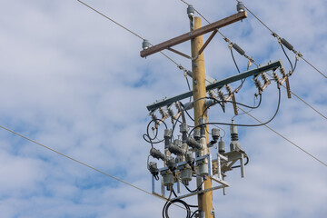 Cables, electrical wires are seen on a wooden electric pole pillar with blue sky background