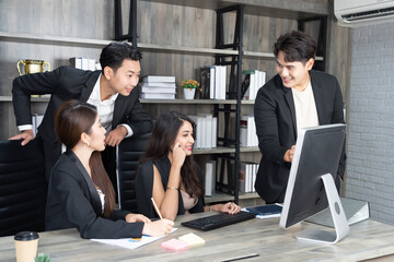 successful business multiage team standing around computer for presentation of work. Group of business people in a meeting at office, working on computer