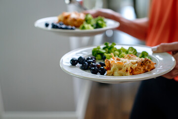 Hands carrying two plates of food