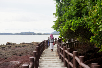 Fototapeta premium Rear view of muslim woman wearing hijab fashion walking on walkway concrete at the island