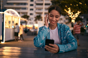 Modern, trendy and happy woman texting on a phone, listening to music and smiling while browsing...