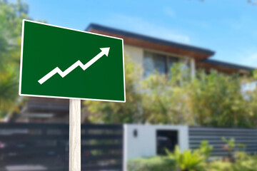 A sign showing an upward arrow in front of a gated house. Concept of increasing home prices and...