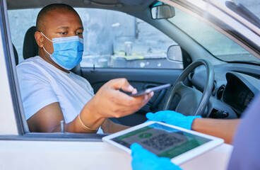 Fototapeta na wymiar Covid drive thru checkpoint man scanning QR code on a tablet with his phone traveling in a car. Man driving wearing a face mask at a coronavirus screening service using technology to send details