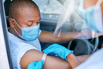 Mobile covid vaccine service outdoors for a patient driving in a car. A healthcare professional applying a plaster on a patient in a vehicle after coronavirus treatment at a vaccination station