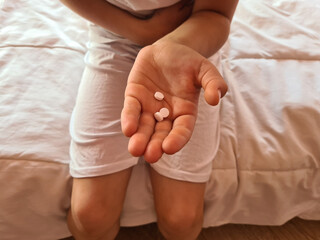 Child suffers from abdominal pain and holds medical pills