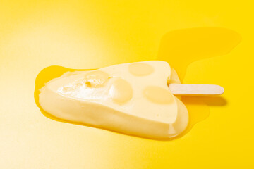 cheese shape and flavor popsice melted on yellow at side angle view