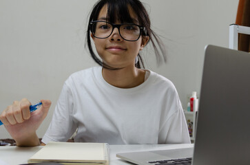 girl holding pen writing book study learning digital internet video online computer laptop at home.