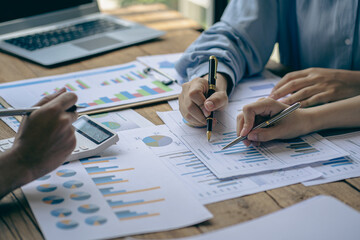 A diverse group of international executive business partners discuss reports at the board of directors' table. The team is negotiating a project, developing a business strategy, analyzing, calculating