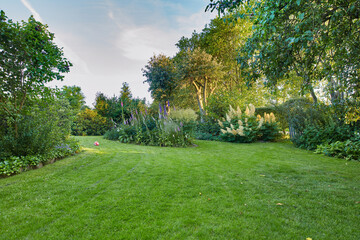 My garden. Well kept garden, park or yard with green grass, trees and flowers growing on a...