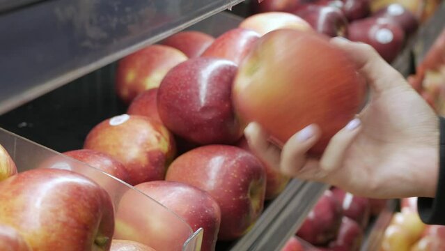 hand pick fresh apple fruit from shelf in supermarket store. choose fruit for healthy food southeast asia life