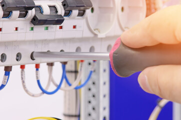 An electrical engineer installs modules in the control panel with a screwdriver.Sunflare.