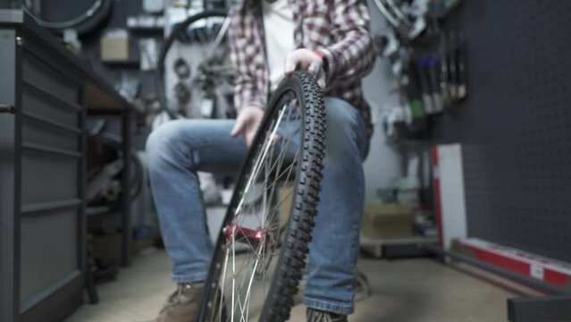 A bicycle mechanic changes a bike tube and tire and fixes a cycle wheel at a repair shop. Bicycle tire care. Technician are fixing bicycle wheel. Engineer at his workplace in the studio