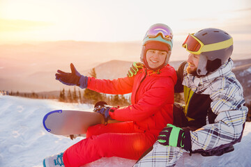 Snowboarders guy and woman hugging at sunset, live photos of active winter sports