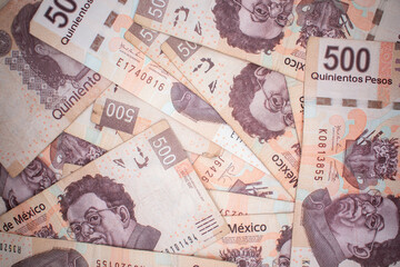 Fototapeta na wymiar Billetes de quinientos pesos mexicanos desordenados en un fondo aleatorio 
