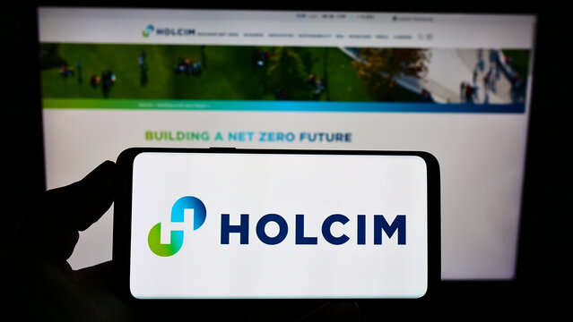 Stuttgart, Germany - 09-01-2022: Person holding smartphone with logo of Swiss building materials company Holcim Limited on screen in front of website. Focus on phone display.