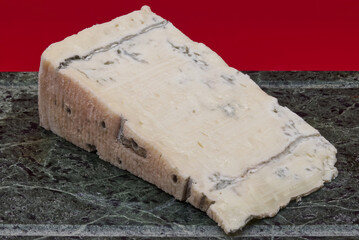 Slice of Italian Gorgonzola cheese isolated on green marble table