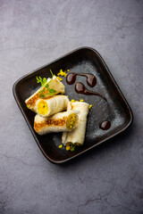 Indian paneer bread roll made using spiced grated cottage cheese mixed with spices & rolled & baked