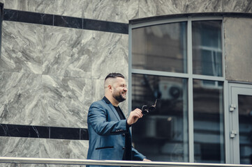 Stylish man in a blue suit in the city.ortrait of a successful smiling businessman.The man greets with gestures.