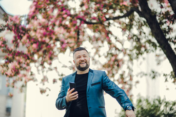 Handsome middle-eastern guy businessman posing next to office center.The guy is laughing and standing in the park.The man laughs a lot. Portrait of a happy successful man.