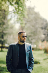 A stylish man in black glasses and a business suit is waiting for a meeting.