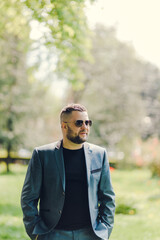 A stylish man in black glasses and a business suit is waiting for a meeting.