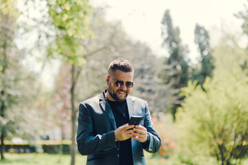 Handsome middle-eastern guy businessman posing next to office center.Worried European business people looking at wristwatch and talking on mobile with colleagues that late appointment in the city.
