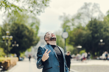 A man in a stylish suit smiles in the middle of the street.