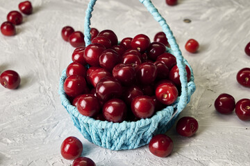 red ripe cherries in a wicker blue basket on the table