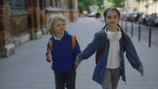 Patriotic kids walking around the street. The boy walking with his sister and holding her hand and american flag. Children come back to school