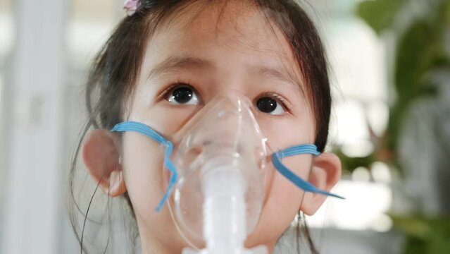 Kid girl making makes inhalation nebulizer steam sick cough at home, Asian Child using nebulizer mask equipment alone have smoke, stuffy nose and runny, oxygen spray inhaler therapy, Health medical