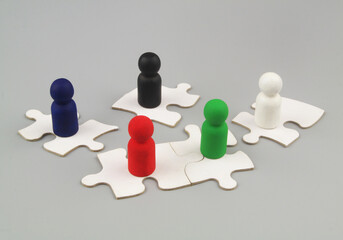 Team building concept. Many people figures on white puzzles on gray background.