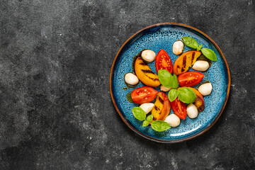 Grilled peach salad with mozzarella, tomato, green basil and sauce , close up, top view