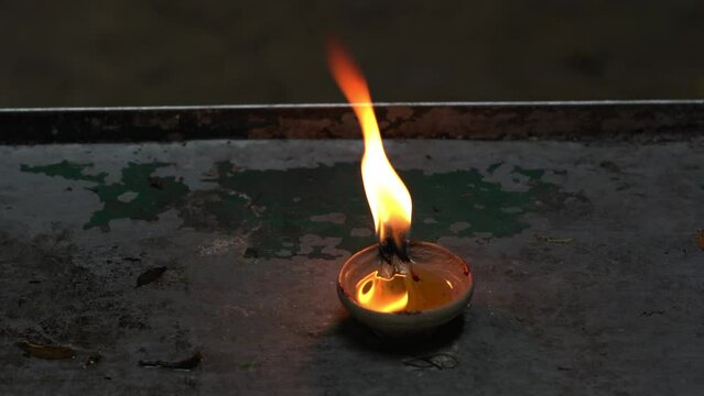 Close up view of a diva oil lamp candle burning and glowing on a table in temple.