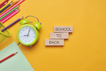 Background with school supplies: books, pencils, alarm clock. Back to school