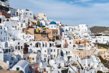 Fototapeta na wymiar Scenic view of Oia town in Santorini with whitewashed houses and a small church with blue domes, Greece