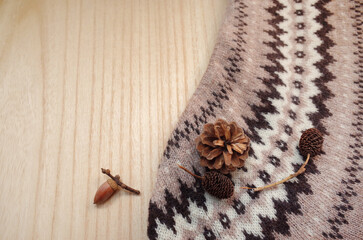 木のテーブルの上にニットと松ぼっくりとドングリとオオバヤシャブシ