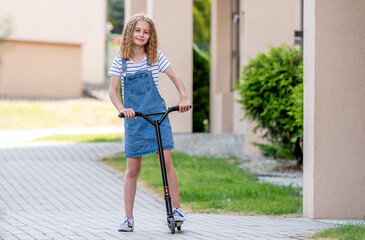 Naklejka premium Little girl rides a kick scooter