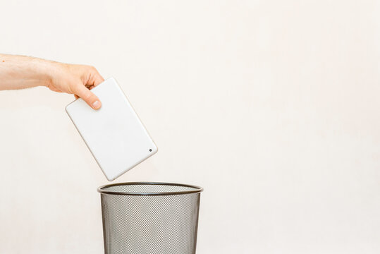The tablet pc is thrown into the trash for disposal and recycling.White,gray background,selective focus,copy space.