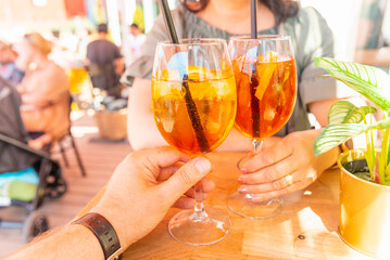 Two cocktail glasses in the middle age man and woman hands in a outdoors cafe.Summer vacation...