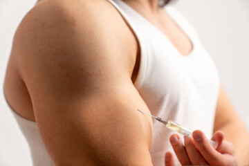 Isolated man taking a vaccine into biceps to prevent serious illnesses. Taking care of his life. High quality photo