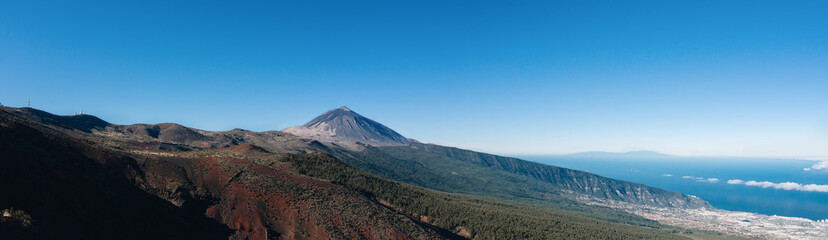 Fototapeta premium Panorama of caldera in Teide National Park, Tenerife, Canary Islands, Spain. Roques de Garcia in the foreground and snow covered mount Pico del Teide in the background.