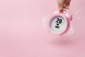 July 20th. Day 20 of month, Calendar date. The morning alarm clock jumping up from the bell with calendar date on a pink background. Summer month, day of the year concept.