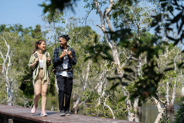 Fototapeta na wymiar Asian active young couple backpacker travel in forest wild together. Attractive man and woman traveler walking and exploring nature wood with happiness and fun during holiday vacation trip on summer.