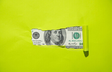 Hole ripped in paper with a dollar.
