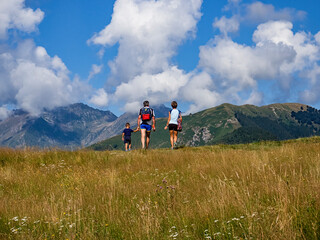 Family walking on a prairie in the alps between Lake Como and Switzerland