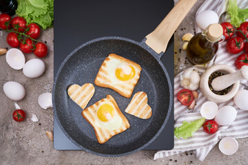 Fried egg Toasts with heart shaped holes on frying pan