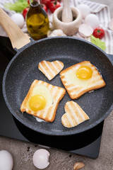 Fried egg Toasts with heart shaped holes on frying pan
