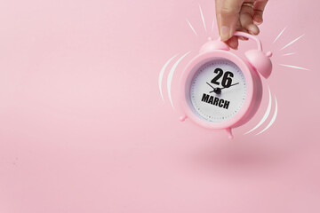 March 26th. Day 26 of month, Calendar date. The morning alarm clock jumping up from the bell with calendar date on a pink background. Spring month, day of the year concept. - Powered by Adobe